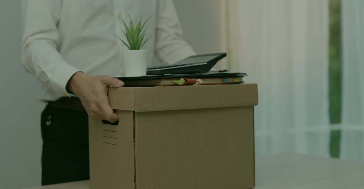 Empleado llevando una caja con pertenencias de oficina, representando la movilidad laboral internacional y la gestión de permisos de trabajo bajo la normativa de extranjería España ICT-UE